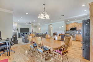 Dining area featuring ceiling fan with notable chandelier, light hardwood / wood-style flooring, and crown molding