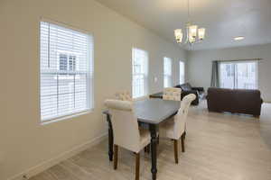 Dining space with a notable chandelier, plenty of natural light, and light wood-type flooring