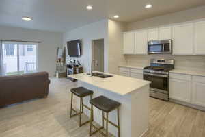 Kitchen featuring white cabinetry, sink, a center island with sink, and appliances with stainless steel finishes