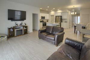 Living room with a fireplace, an inviting chandelier, sink, and light hardwood / wood-style flooring