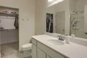 Bathroom featuring vanity, toilet, and a shower with door