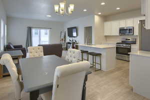 Dining area with sink, light hardwood / wood-style flooring, and a notable chandelier