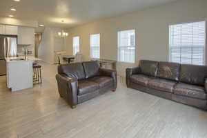 Living room with light hardwood / wood-style floors, a healthy amount of sunlight, sink, and an inviting chandelier