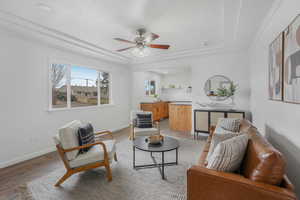 Living room featuring ceiling fan, light wood-type flooring, crown molding, and a tray ceiling