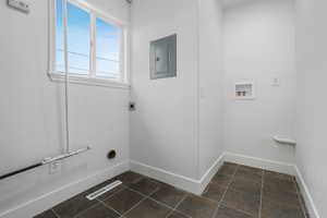 Clothes washing area featuring hookup for an electric dryer, electric panel, and washer hookup