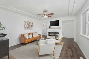 Living room with a wealth of natural light, ceiling fan, and dark wood-type flooring