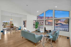 Living room with ceiling fan, light hardwood / wood-style floors, and high vaulted ceiling