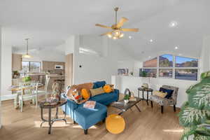 Living room with ceiling fan, high vaulted ceiling, and light hardwood / wood-style floors