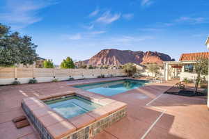 View of swimming pool featuring a mountain view, a patio, and an in ground hot tub