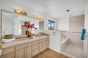 Bathroom featuring wood-type flooring, vanity, tile walls, and tiled tub