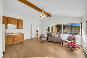 Living area featuring beam ceiling, ceiling fan, sink, light hardwood / wood-style flooring, and high vaulted ceiling