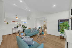 Living room featuring ceiling fan, vaulted ceiling, and light wood-type flooring