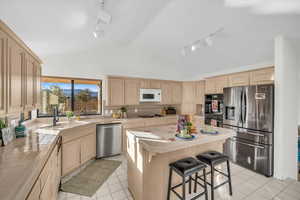 Kitchen featuring tile counters, rail lighting, stainless steel appliances, light tile patterned floors, and a kitchen island