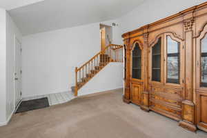 Foyer featuring carpet flooring and vaulted ceiling