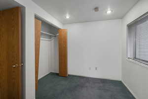 Unfurnished bedroom with dark colored carpet and a closet