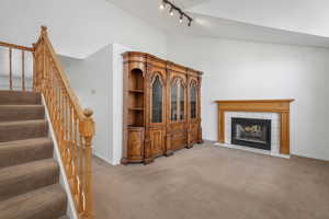 Carpeted living room with a fireplace and vaulted ceiling