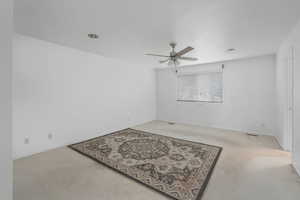 Carpeted empty room featuring ceiling fan