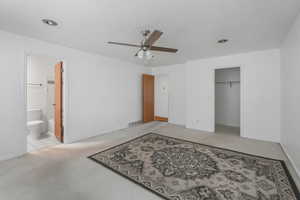 Carpeted bedroom featuring connected bathroom, ceiling fan, a closet, and a spacious closet