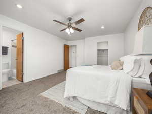 Carpeted bedroom featuring ensuite bath, a walk in closet, a closet, and ceiling fan