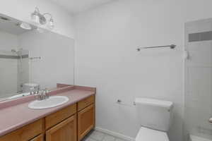 Bathroom featuring tiled shower, vanity, toilet, and tile patterned flooring