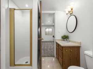 Bathroom featuring vanity, a textured ceiling, a shower with door, and toilet