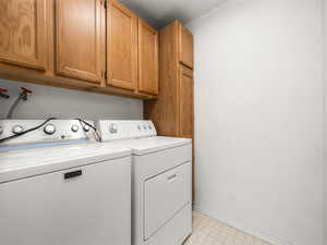 Laundry area featuring washer and clothes dryer and cabinets