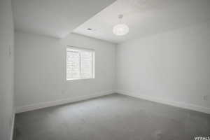 Empty room with dark carpet and a notable chandelier