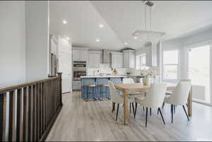 Dining area with a notable chandelier, lofted ceiling, and light hardwood / wood-style flooring