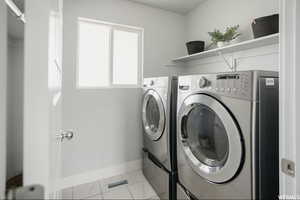 Laundry room featuring washing machine and clothes dryer and light tile patterned flooring