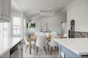 Dining room featuring light wood-type flooring, lofted ceiling, and a notable chandelier