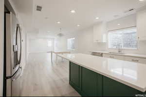 Kitchen featuring white cabinets, sink, appliances with stainless steel finishes, a kitchen island, and a chandelier