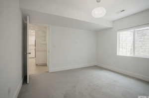 Empty room featuring light carpet and an inviting chandelier