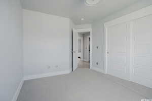 Unfurnished bedroom featuring a closet and light colored carpet