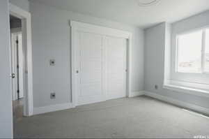 Unfurnished bedroom featuring light carpet and a closet