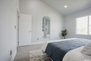 Carpeted bedroom with ensuite bath and lofted ceiling