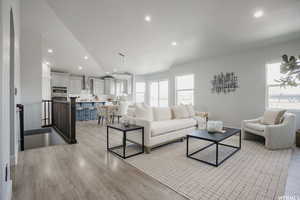 Living room featuring light hardwood / wood-style flooring, a wealth of natural light, and lofted ceiling