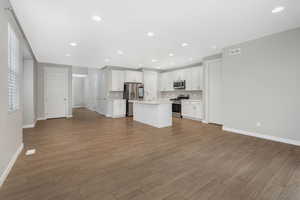 Kitchen featuring white cabinetry, stainless steel appliances, tasteful backsplash, light hardwood / wood-style flooring, and a center island with sink