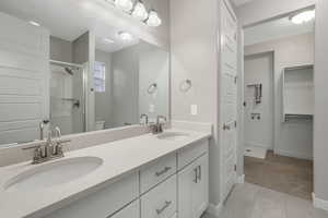 Bathroom featuring tile patterned flooring, vanity, toilet, and a shower with door