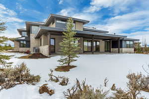 Snow covered rear of property featuring central air condition unit