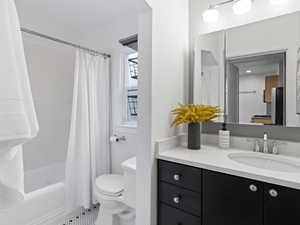 Full bathroom with tile patterned floors, shower / bath combination with curtain, toilet, and vanity