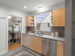 Kitchen with stainless steel dishwasher, light brown cabinets, sink, and light hardwoo flooring