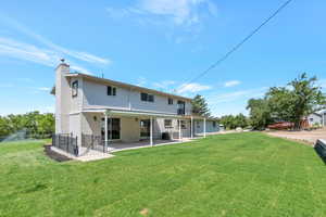 Rear view of house featuring a lawn, central AC unit, and a patio area