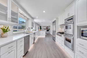 Kitchen featuring decorative backsplash, white cabinetry, stainless steel appliances, and light wood-type flooring