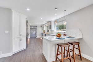 Kitchen featuring kitchen peninsula, white cabinetry, dark hardwood / wood-style flooring, and pendant lighting