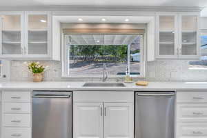 Kitchen featuring dishwasher, decorative backsplash, white cabinetry, and sink