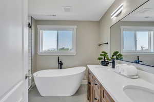 Bathroom with tile patterned floors, a tub, and vanity