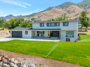 View of front of house with covered porch, a mountain view, a garage, and a front lawn