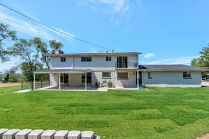 Rear view of property with a lawn, a balcony, and a patio