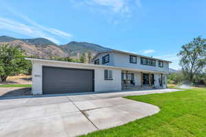 View of front facade featuring a mountain view, a garage, covered porch, and a front lawn