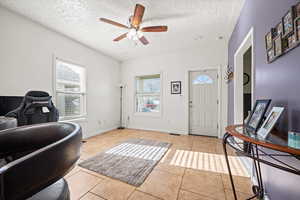 Entryway with ceiling fan, light tile patterned floors, and a textured ceiling